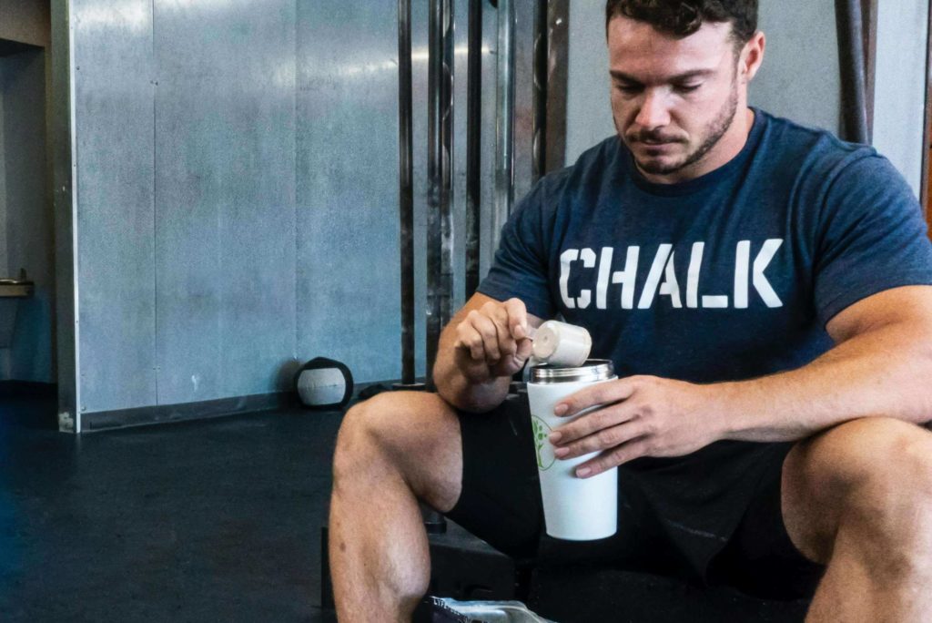 Man Adding Supplement to Shaker at Gym