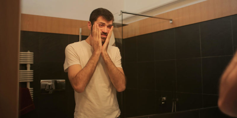 Hungover Man Looking at Himself in Mirror